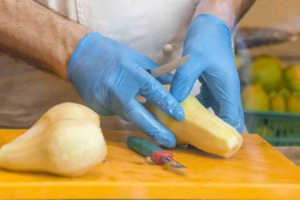 Cook in blue gloves cuts a pear
