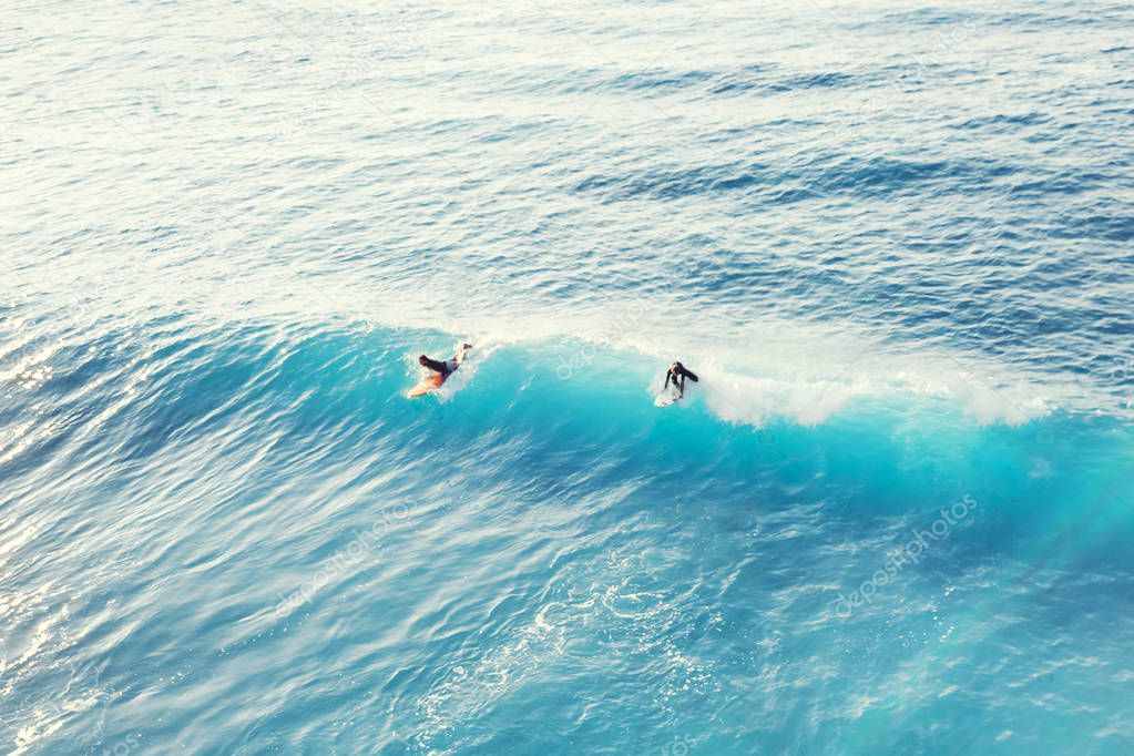 Two surfers at the top of the wave in the ocean, top view