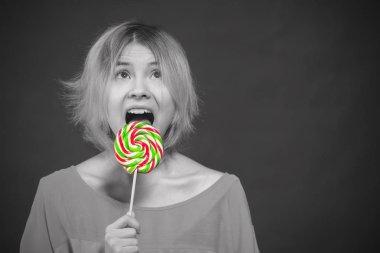Sarışın kız Genç bir lolipop yalamak. Tonda