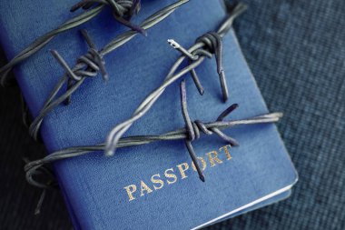 Arkasında dikenli tel bir mavi Tekstil zemin üzerine mavi pasaport yakın çekim. Tonda