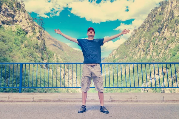 Человек Шапке Стоит Поднятыми Руками Дороге Горах — стоковое фото