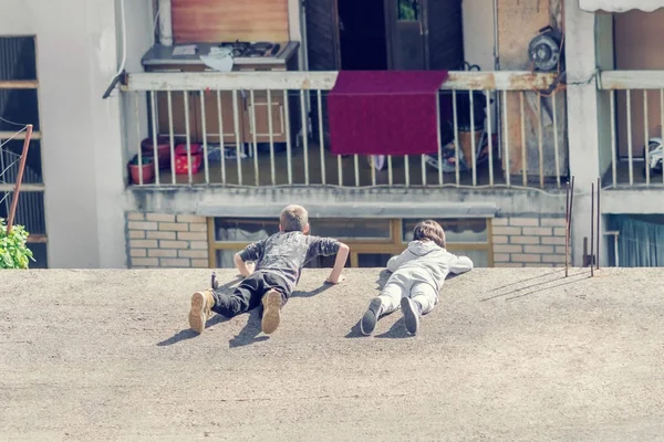 Двое Детей Лежат Краю Крыши Смотрят Вниз — стоковое фото