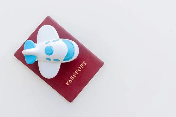 Small toy plane on top of a red passport on a white background