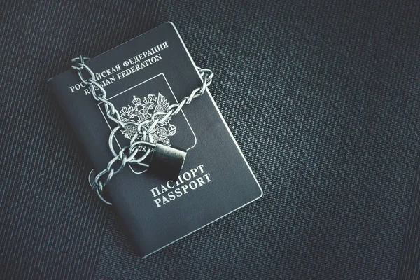 Russian Passport covered with a chain with a golden lock on a textile background. Toned