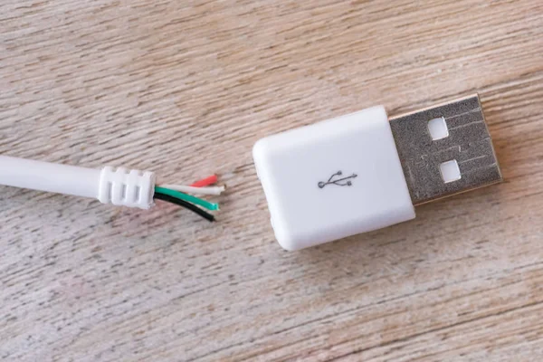 Broken white usb cable on a wooden table