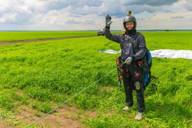 Kazan, Rusya, 16 Haziran 2017: Adam kıyafeti uçuş öncesi yeşil çimenlerin üzerinde elini sallayarak yamaç paraşütü için