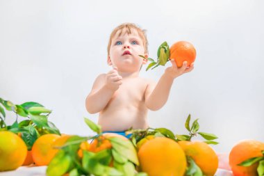Bir portakal tutan erkek sarışın bebek