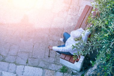 Bastonla bir bankta oturan yaşlı bir adam üstten görünüm