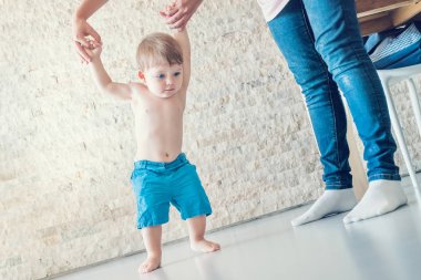 Şirin mavi gözlü bebek çocuk annesinin yardımıyla yürümeyi öğrenir