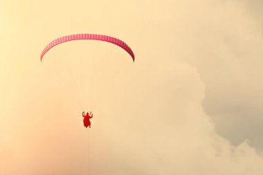 Gün batımında gökyüzünde kırmızı yamaçparaşütü