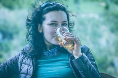 Güzel esmer kadın bir bardaktan bira içer. Tonda