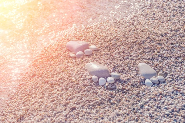 在阳光下的冲浪线上用石头做的足迹 — 图库照片