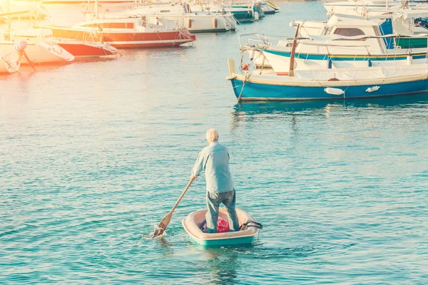 老人在阳光下乘小船航行到游艇泊位 — 图库照片
