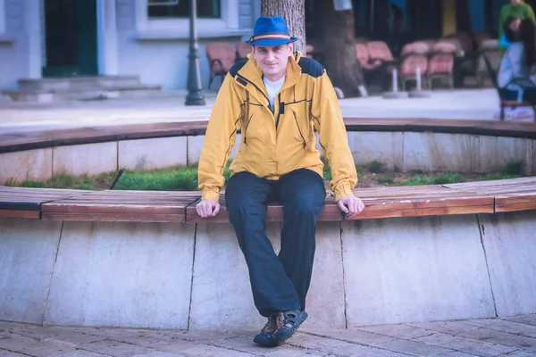 도시의 벤치에 노란색 재킷과 모자에 — 스톡 사진