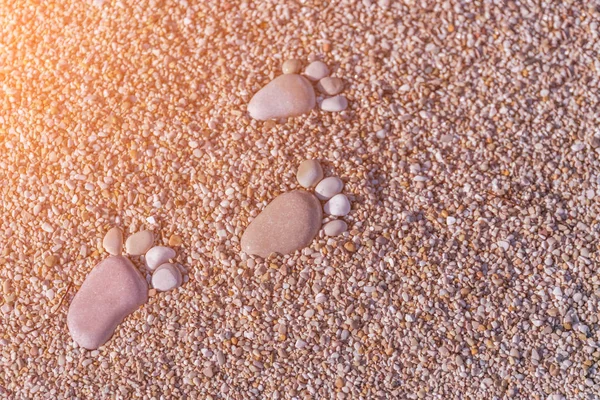フット プリントは 日光の下で砂の上の小石から成っています トーン — ストック写真