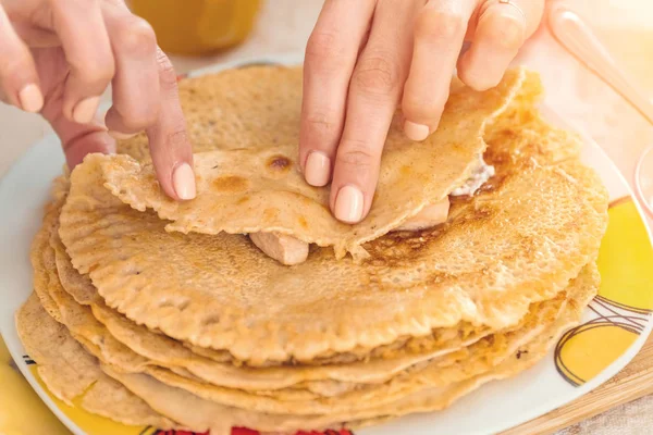 Women's hands wrap stuffing in pancakes