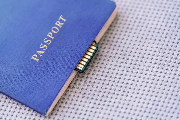 Blue Passport with memory card on a gray textile background