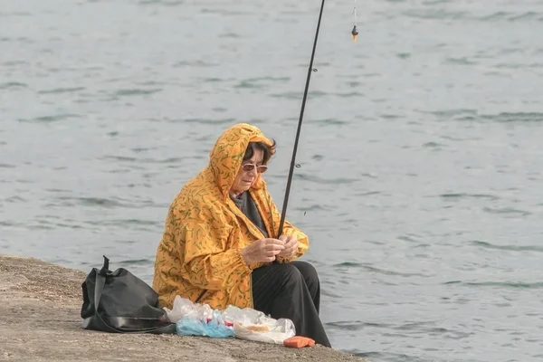 コトル モンテネグロ 2017年4月28日 釣り竿を持つ黄色いジャケットを着た女性が海岸から釣りをしています — ストック写真