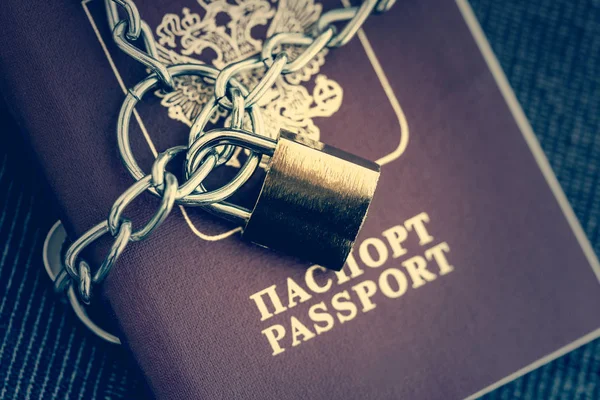 Russian Passport covered with a chain with a golden lock on a textile background, close-up. Toned