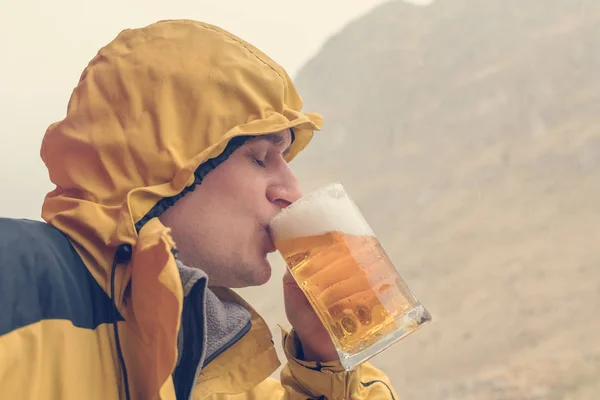Volwassen Man Een Gele Jas Drinkt Bier Uit Een Mok — Stockfoto