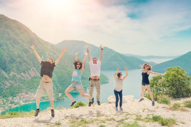 Kotor, Karadağ, 28 Nisan 2017: Bir grup mutlu insan güzel bir manzaraya karşı bir dağın tepesinde atlıyor