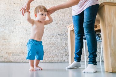 Şirin mavi gözlü bebek çocuk annesinin yardımıyla yürümeyi öğrenir