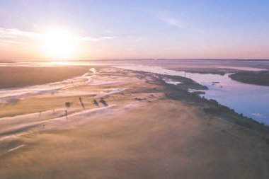 Field and river covered with fog at sunrise, top view