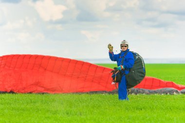 Kazan, Rusya, 16 Haziran 2017: Adam elini sallayarak açılış sonra yeşil bir alan üzerinde kırmızı bir yamaçparaşütü ile