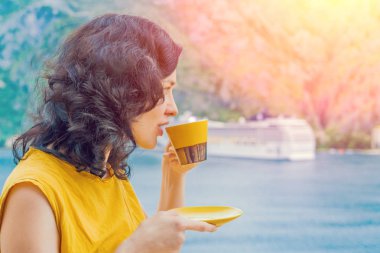 Denizin arka planda sarı bir kupa kahve içme güzel esmer kadın