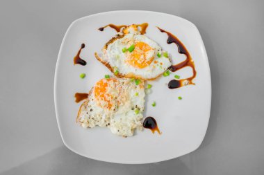 Kızarmış yumurta yeşil soğan ve beyaz tabakta sos ile