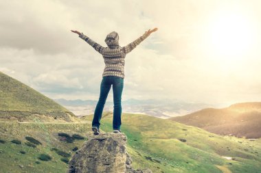 Bir ceket ve kot kadının elleri ile dağların arka plana karşı bir uçurumun üstünde ayakta kadın