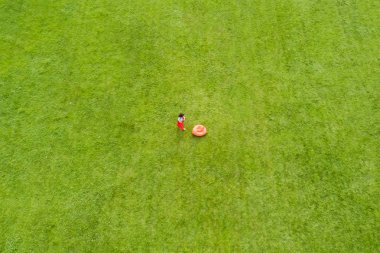 Yeşil çim üzerinde bir kadının büyük bir portakal yastık ile üstten görünüm