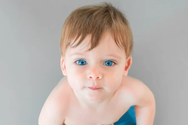 灰色の背景に青い目をした金髪の男の子の肖像画 — ストック写真