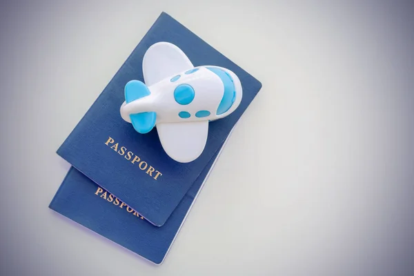 Small toy plane on top of a blue passport on a white background