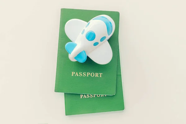 Small toy plane on top of a green passport on a white background