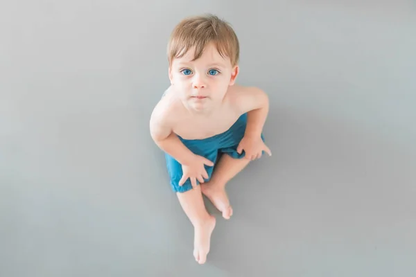 Blonde Baby Boy Blue Eyes Blue Shorts Sitting Gray Background — Stock Photo, Image