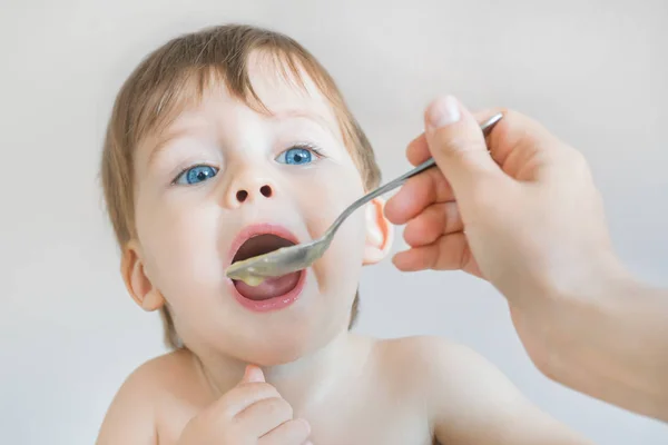 Cute Small Blue Eyed Blond Boy Eating Puree Spoon Stock Photo