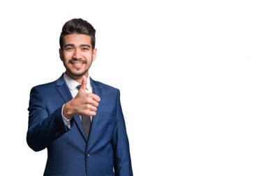 Beyaz bir arka plan üzerinde başparmak gösterilmesini mavi elbiseli Genç çekici adam. İzole