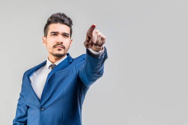 Bir parmak ileri gri bir arka plan üzerinde gösterilen mavi elbiseli Genç çekici adam. İzole