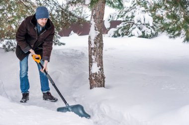 Adam kış giysileri kar küreği avlu üzerinde temizler