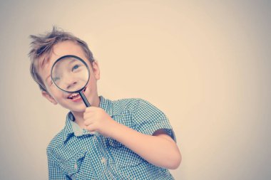 Sevimli çocuk mavi gömlekli bir büyüteç arıyor. Tonda