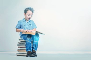 Yakışıklı bir yığın kitap üzerinde oturan bir kitap okuma mavi gömlekli