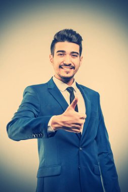Bir başparmak-up gösterilen mavi elbiseli Genç çekici adam. Tonda