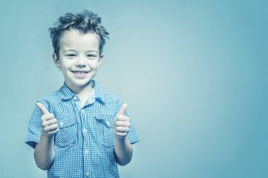 Mavi gömlekli başparmak mavi bir arka plan üzerinde gösterilen boy gülümseyerek. Tonda