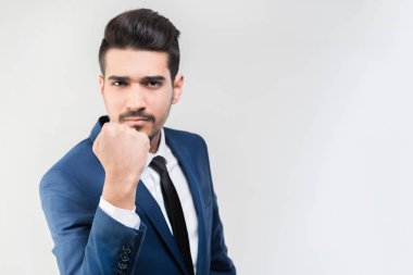 Bir yumruk gri bir arka plan üzerinde gösterilen mavi elbiseli Genç çekici adam. İzole