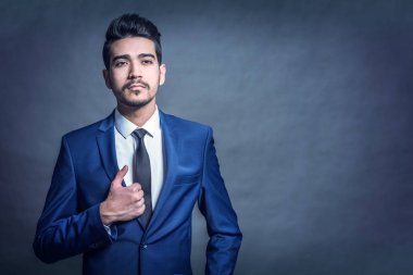 Gri bir arka plan üzerinde mavi elbiseli Genç çekici adam. Tonda