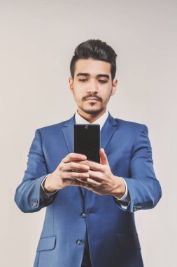 Telefonun ekranına bakarak mavi elbiseli Genç çekici adam. Tonda