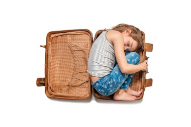 Kız beyaz bir arka plan üzerinde eski bir kahverengi bavul içinde yatıyor. İzole