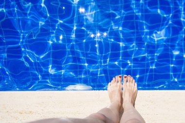 Kadın ayakları kırmızı oje ile havuz kenarına yakın: