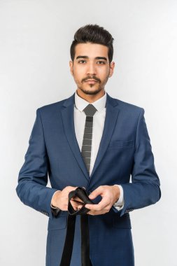 Kravat beyaz bir arka plan üzerinde elinde tutan mavi elbiseli Genç çekici adam. İzole